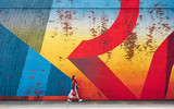 Fototapeta Młodzieżowe - Young girl walking by the wall with graffiti