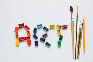 Wall Mural - top view of paintbrushes, pencil and art lettering made of paints on white background