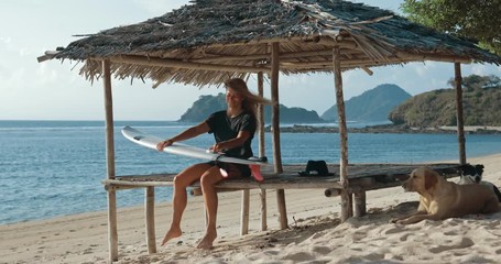 Wall Mural - Girl surfer waxing her surfboard