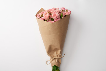 bouquet of beautiful pink roses wrapped in craft paper on grey