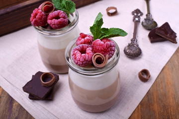 Wall Mural - Three chocolate mousse dessert in a glass jar garnished with frozen raspberries