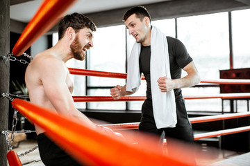 Wall Mural - Boxing trainer giving instructions during a break motivating a boxer sitting on the corner of the boxing ring