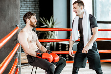 Wall Mural - Boxing trainer giving instructions during a break motivating a boxer sitting on the corner of the boxing ring