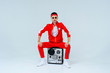 © lanarusfoto - cheerful fashionable man wearing a red sports suit sitting with a retro tape recorder. proud and successful style of the 90's