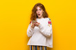 © luismolinero - Young redhead woman over yellow wall surprised and sending a message