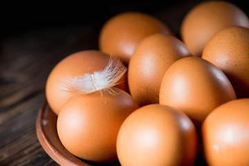 Wall Mural - chicken eggs in a clay plate on a wooden table