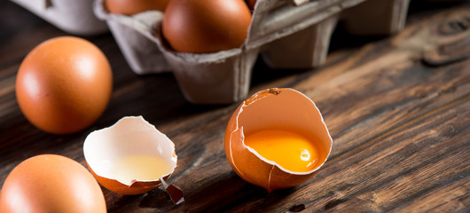 Wall Mural - Fresh brown eggs on rustic table. Broken egg with yolk.