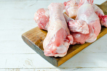 Raw uncooked chicken legs, drumsticks on wooden board, meat with ingredients for cooking