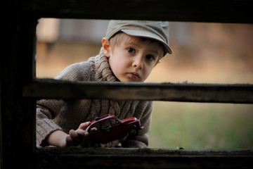 Little cute boy is looking at something astonished. The child plays with a toy car in a forbidden place.