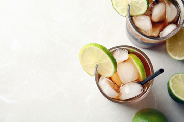 Wall Mural - Glasses of cocktail with cola, ice and cut lime on light background, flat lay. Space for text