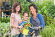 © coldwaterman - Gärtnerin zeigt lächelnd einer Kundin mit Sohn eine Tomatenpflanze