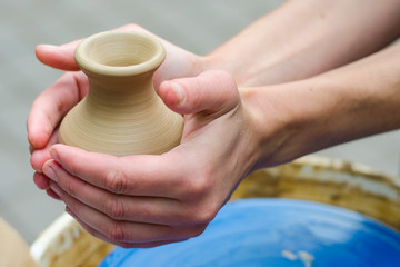 clay pot and hands that created it. Handmade vase making with wet clay and hand potter's wheel In the pottery workshop