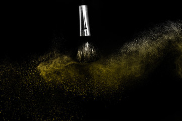 Wall Mural - Cosmetic brush with golden cosmetic powder spreading for makeup artist and graphic design in black background