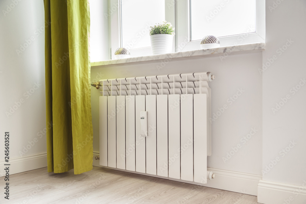 Heating white radiator radiator in living room. - obrazy, fototapety, plakaty 