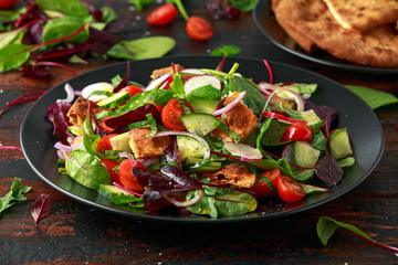 Traditional fattoush salad on a plate with pita croutons, cucumber, tomato, red onion, vegetables mix and herbs