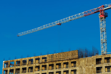 Tower crane at the construction site against the blue sky