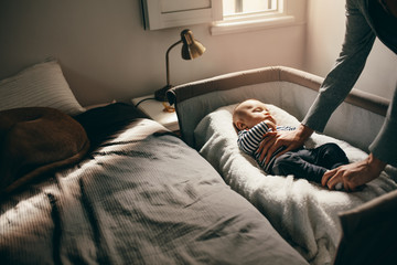 Wall Mural - Mother looking at her baby sleeping in a crib