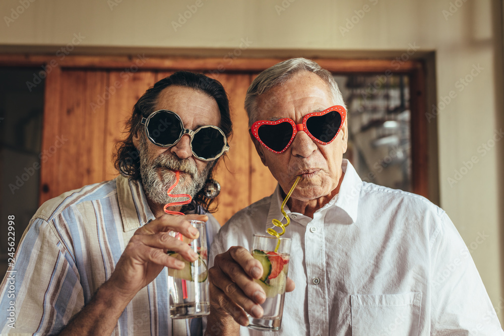 Retired men wearing funny sunglasses drinking juice - obrazy, fototapety, plakaty 