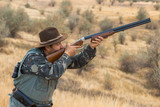 Fototapeta Sport - Hunter with a hat and a gun in search of prey in the steppe	