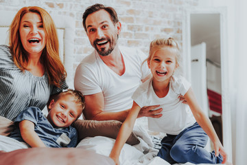 Wall Mural - Happy laughing family posing on camera in bed