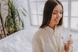© Yakobchuk Olena - Smiling young girl keeping glass of water with medicine in apartment
