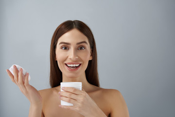 Wall Mural - Happy young lady holding opened jar of cosmetic cream