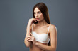 © Yakobchuk Olena - Attractive brunette girl in white bra standing against blue-gray background