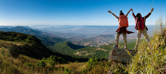 Wall Mural - two female hikers climbing up mountain cliff