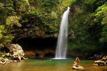 Wall Mural - Young woman in bikini sitting by Lower Tavoro Waterfalls in Bouma National Heritage Park, Taveuni Island, Fiji