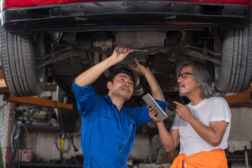 Two mechanic engineer repair the car and checklist fix item with tablet in the garage  - Image