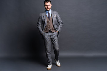 Wall Mural - Full length portrait of a fashion male model over grey background. Looking at camera.