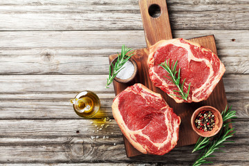 Wall Mural - Fresh meat on wooden cutting board top view. Raw beef steak and spices for cooking.