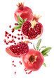 Flying in air fresh ripe whole and cut pomegranate with seeds and leaves