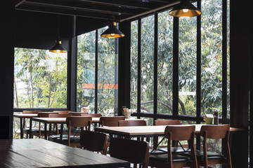 Table and chair set in modern cafe minimalistic interior design with big window and hanging ceiling lamps