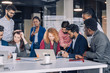 © alfa27 - Creative multiracial business team discussing project, standing around workplace, while two co-workers with portable computers looking for needed information, sharing results to the workers