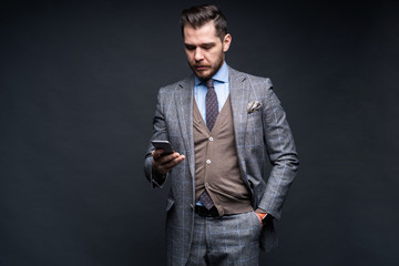 Wall Mural - A man in a business suit with a smartphone. Studio portrait.