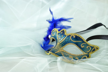 Photo of elegant and delicate silver and blue venetian mask over mint chiffon background.