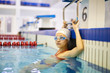 © Seventyfour - Portrait of young girl in swimsuit and swimming goggles doing exercises in the water near the edge of the pool