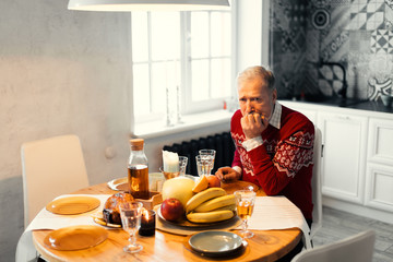 unhappy old man is waiting for his relatives. gey-haired man is celebrating Chritmas alone.