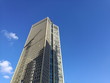 Schatten eines Baukran auf der Fassade eines naturfarbenen Wolkenkratzer vor blauem Himmel im Sonnenschein im Gallus am Europaviertel in Frankfurt am Main in Hessen