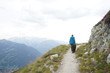 © Kriste - Male hiker and a Bernese Mountain Dog walking on the path in the mountains, Alps, Switzerland
