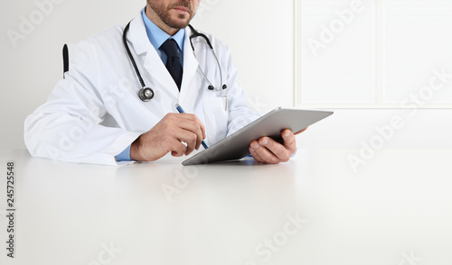 Doctor At Desk Office Write On Digital Tablet Isolated On White