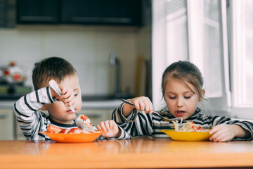 Wall Mural - Boy and girl in the kitchen eating pasta