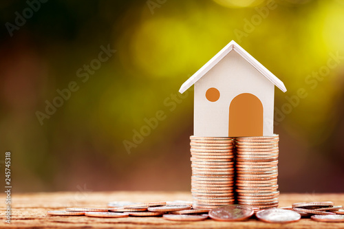 Fotografía Loan or saving money for buy a house and real estate for family concept, Home model put on the stack coin tower with growing business investment in the in the public park