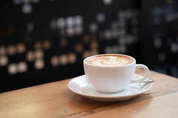 coffee latte in a white cup on wooden table in coffee shop.