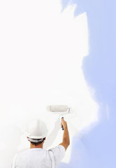 Wall Mural - Rear view of painter man with paint roller painting on blank wall, isolated on white, copy space template