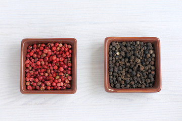 two colors condiments. red and black pepper in different plates top view