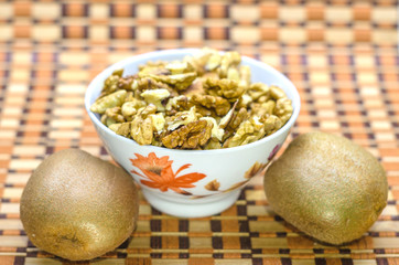 Wall Mural - Walnuts in a white bowl on a brown beautiful background.