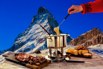 Fototapete - Fondue cheese, swiss winter ski holidays break for lunch, mountain view Matterhorn in Zermatt, Switzerland.