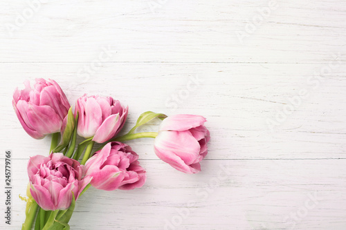 Pink tulips on white wooden background with copy space. Top view.